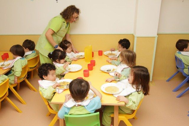 Escuela Infantil Los Robles profesora con niños y comida