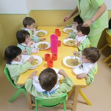 Escuela Infantil Los Robles mujer dando de comer a niños
